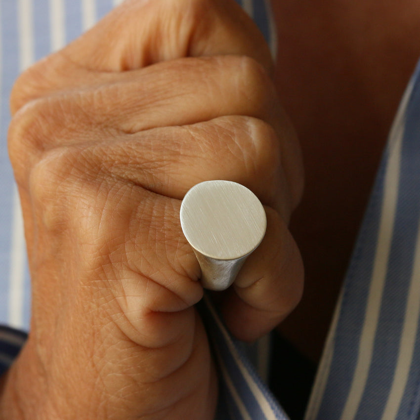A 20 mm round silver signet ring worn on a hand