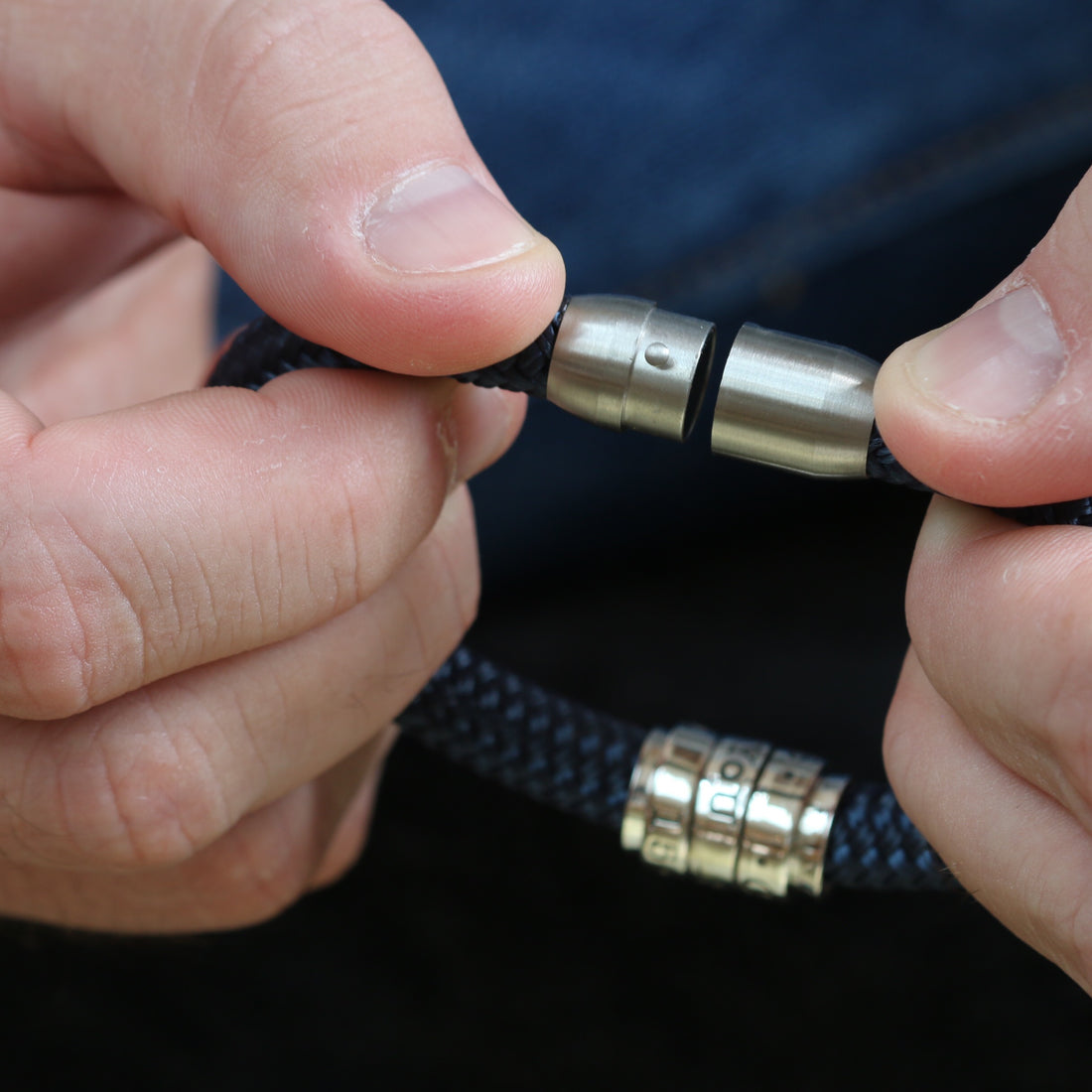 Hands showing the twist-and-lock clasp on a paracord bracelet