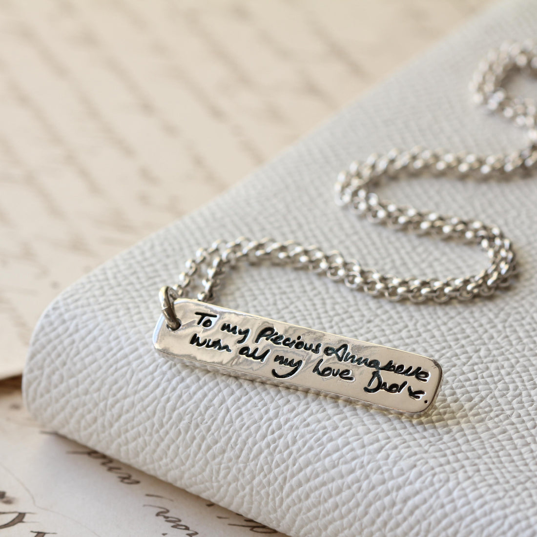 A silver handwriting ingot pendant on fabric