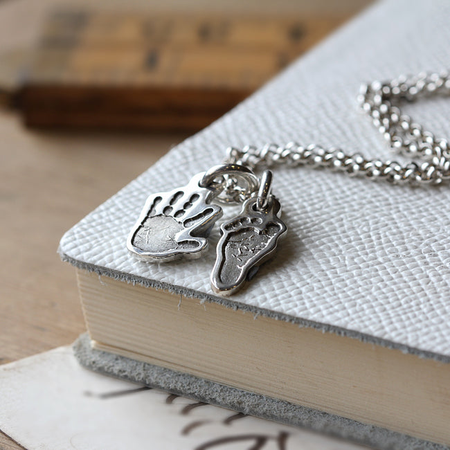 Silver hand-shaped and foot-shaped charms shown together