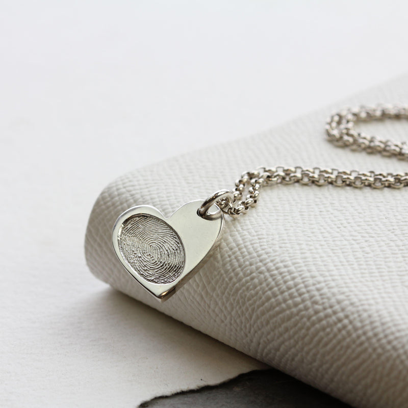 Silver Heart Fingerprint Necklace resting on linen