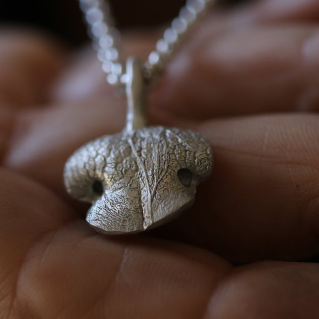 Close-up of the polished edge and natural dog nose texture on a rounded Snozza pendant.