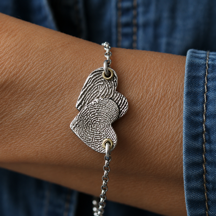 Silver Entwined Hearts Bracelet worn on a wrist, shown with two fingerprints.