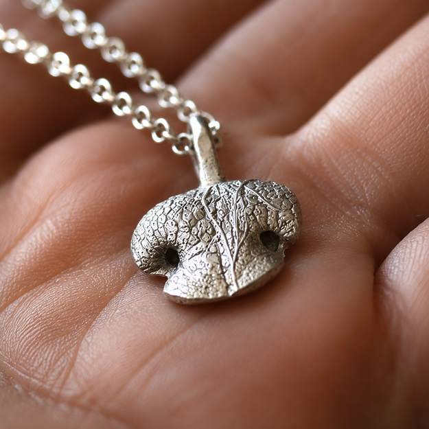 Close-up of a rounded sterling silver Snozza necklace.