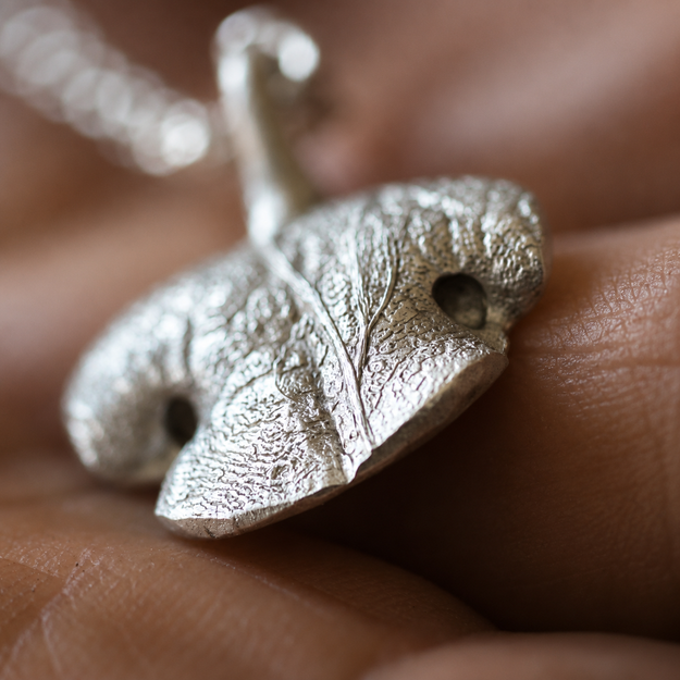 Side view of the handcrafted rounded Snozza pendant showing its organic shape and thickness.