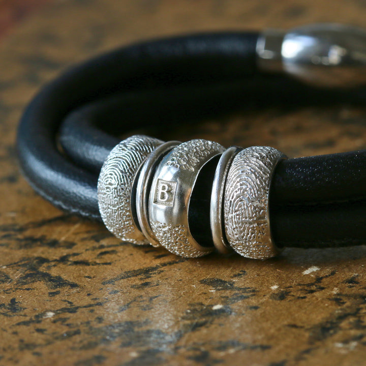 Heirloom Story Bracelet with silver fingerprint and dog nose print beads on black leather.