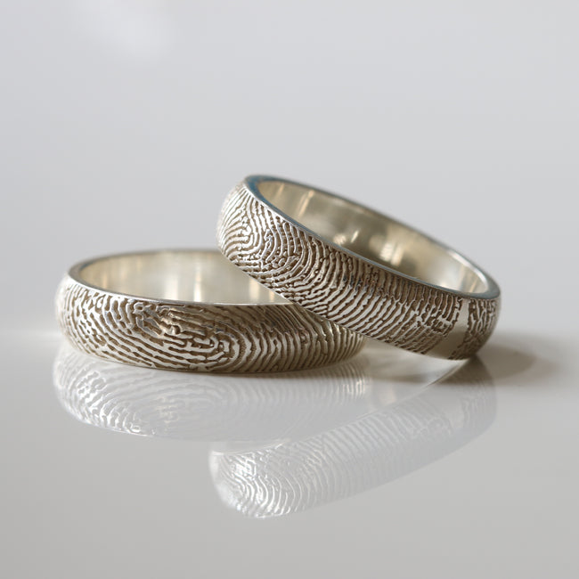 Silver rings with engraved fingerprint patterns