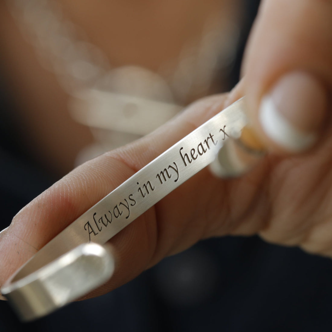 An engraved silver cuff held in the hand, showing its scale