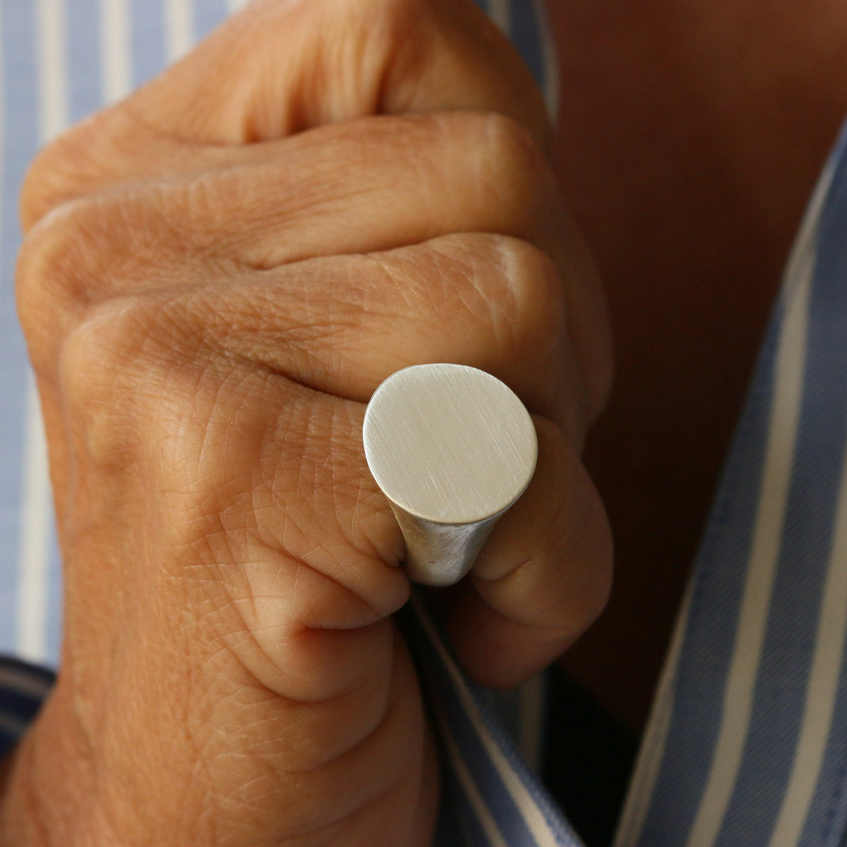 A 20 mm brushed matt sterling silver round signet ring worn on a hand