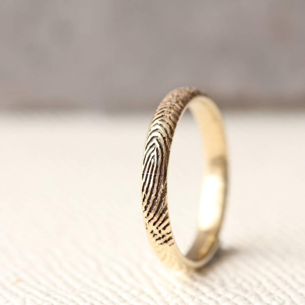 Single solid gold fingerprint ring standing upright