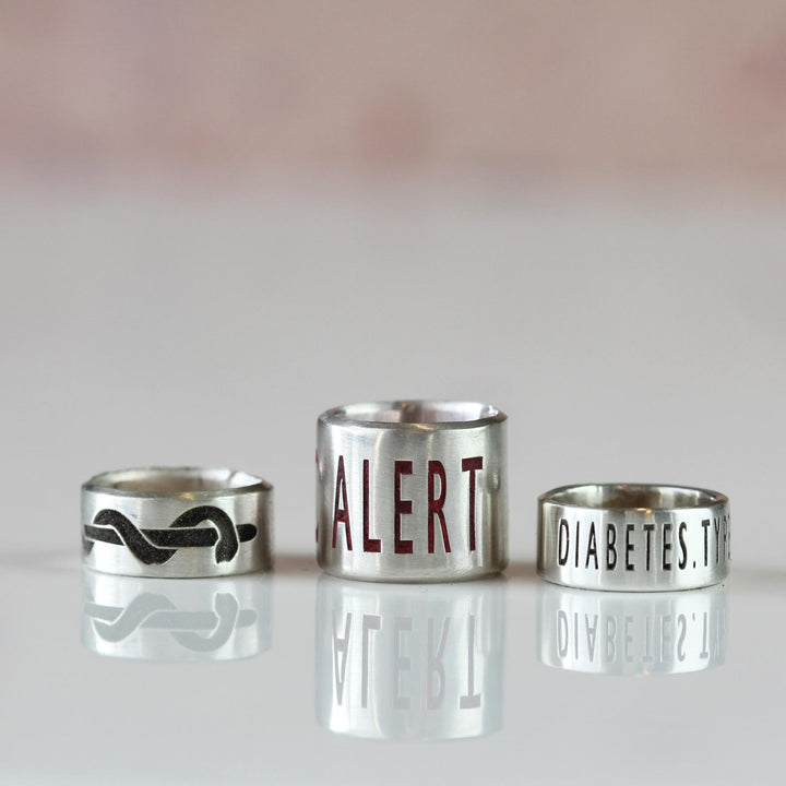 Silver medical alert beads showing a symbol and engraved text