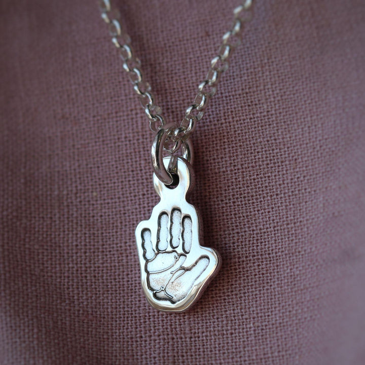 Silver charm shaped around a handprint