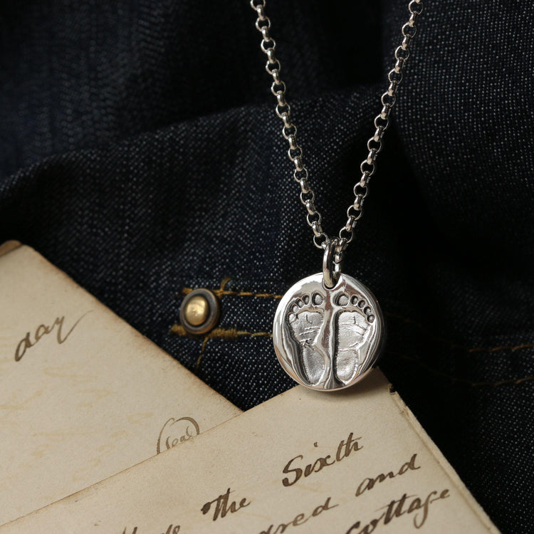 Round silver pendant with two footprints