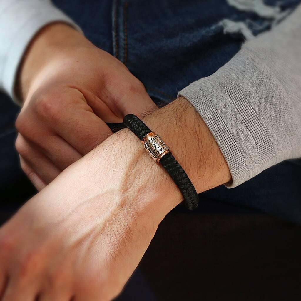 A navy paracord bracelet with personalised silver rings worn at the wrist