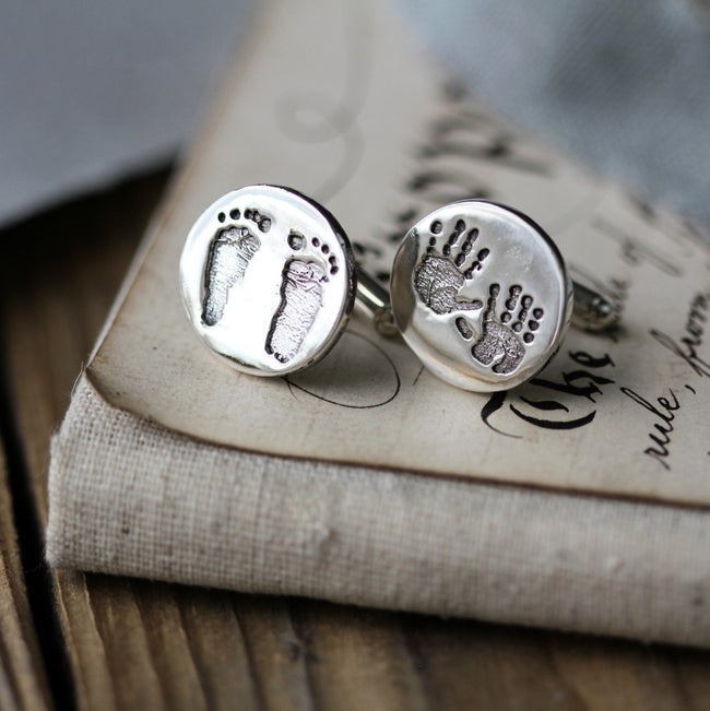 Round silver cufflinks with handprints and footprints