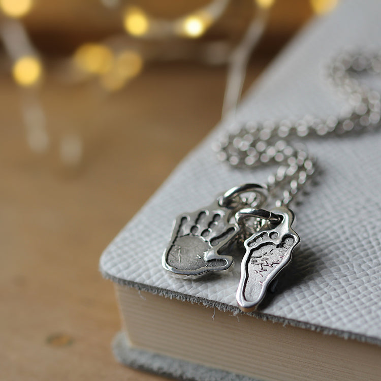Silver hand-shaped and foot-shaped charms on a chain