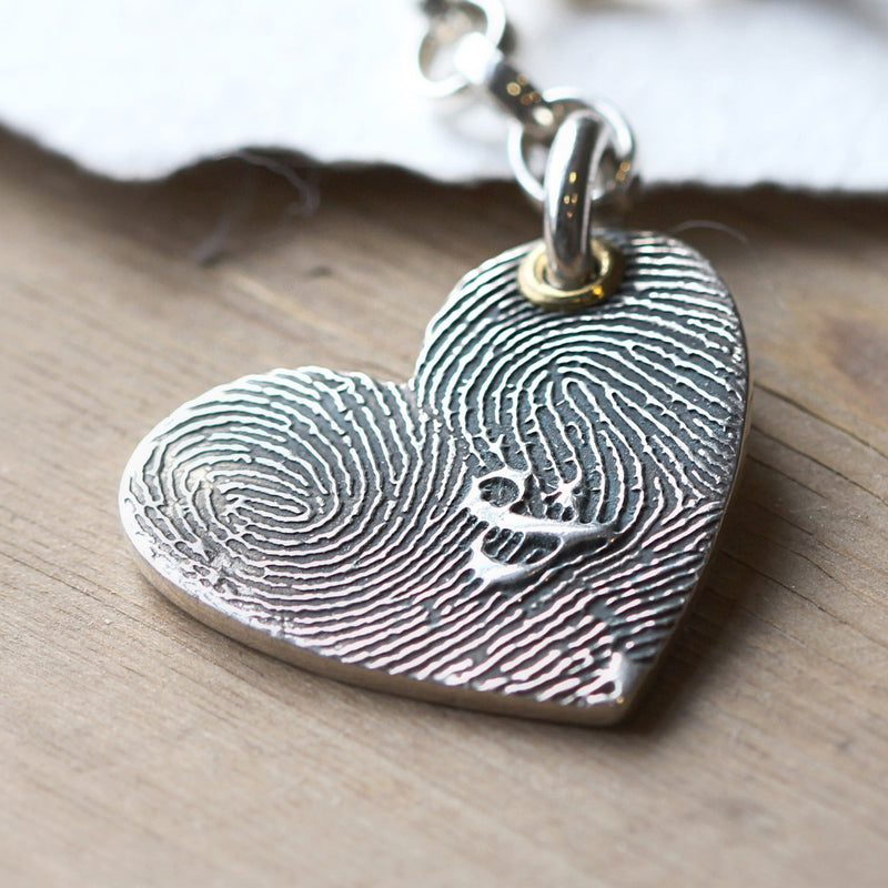 Silver heart pendant showing two fingerprint patterns