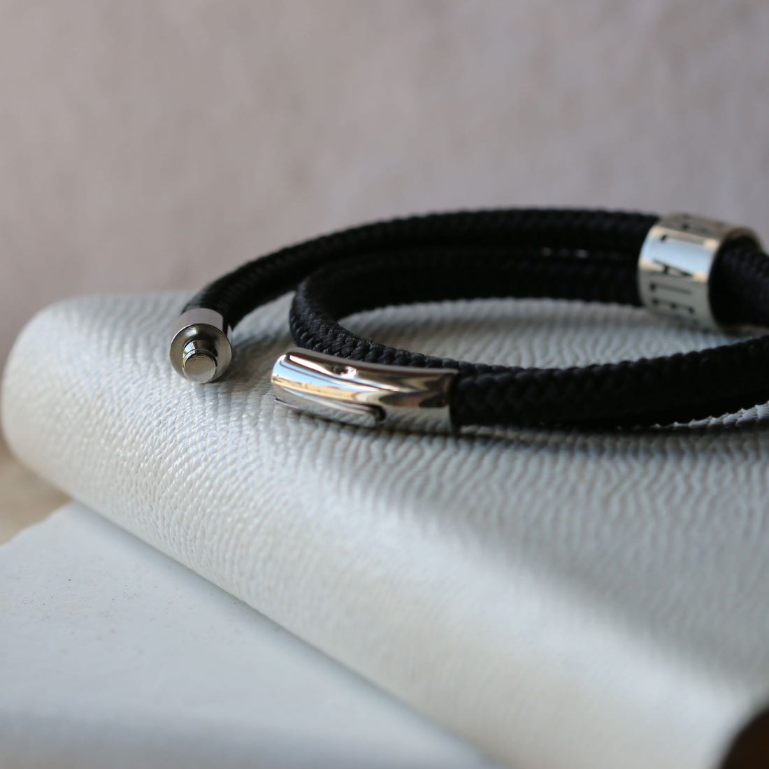 Close-up of the clasp on a black braided leather bracelet